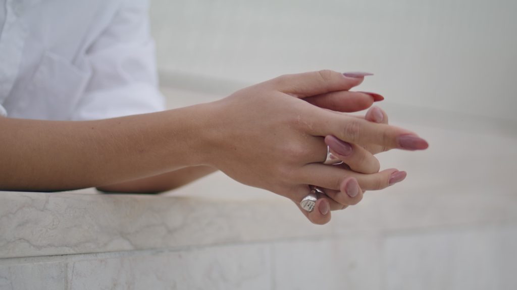 Tender woman hands with crossing fingers wearing stylish ring close up